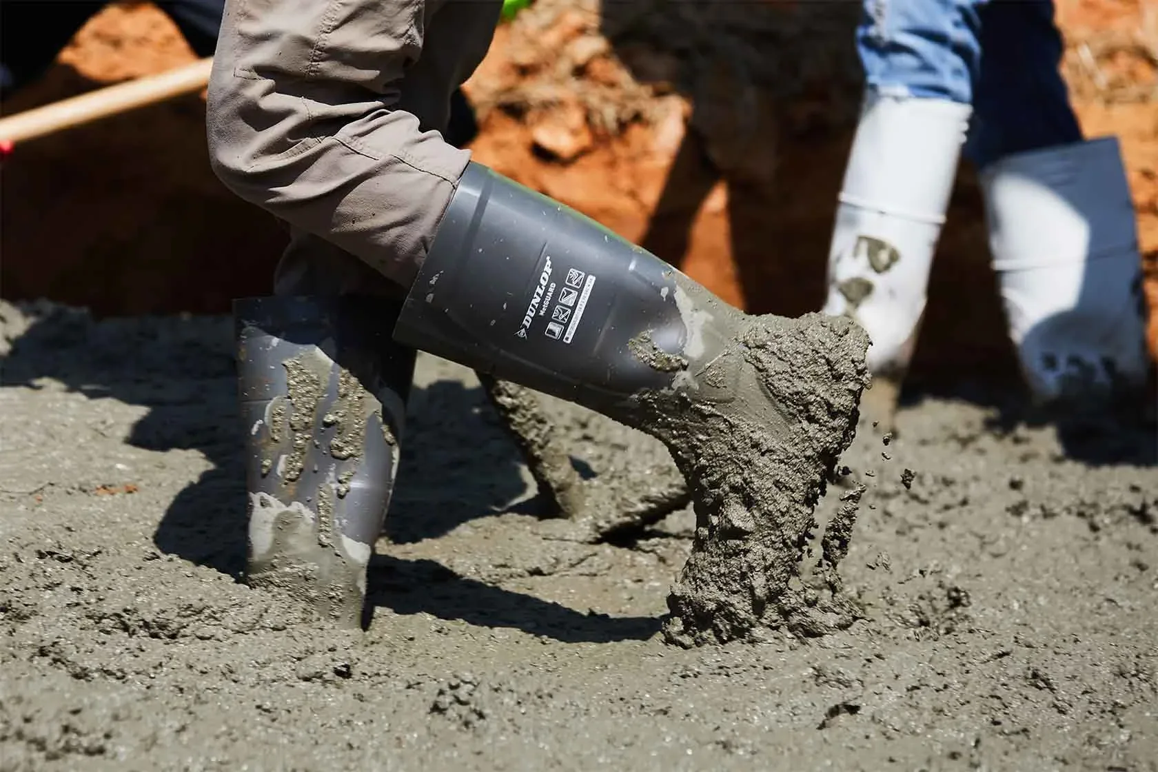 A Dunlop safety boot on a construction site, covered in concrete